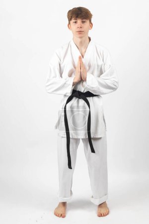 Photo for A 15 year old Karate Blackbelt boy, wearing A Gi performing a sign of respect - Royalty Free Image