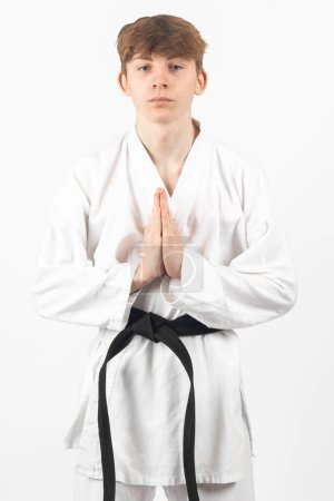 Photo for A 15 year old Karate Blackbelt boy, wearing A Gi performing a sign of respect - Royalty Free Image