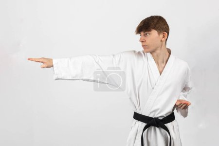 Ein 15-jähriger Karate Blackbelt Junge, der A Gi trägt und eine Kata vorführt