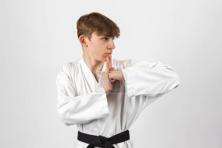 Ein 15-jähriger Karate Blackbelt Junge, der A Gi trägt und eine Kata vorführt