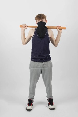 Ein männliches Bandenmitglied mit Maske und Baseballschläger über den Schultern