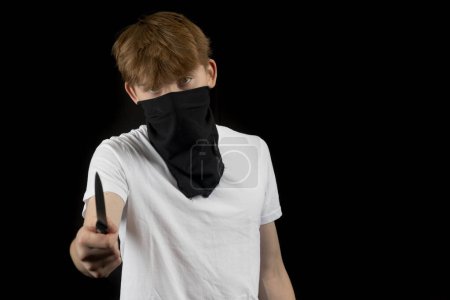 Un agresseur masculin adolescent contre un fond noir tenant un couteau
