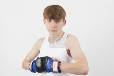 Photo for A 15 year old male teenager boxer, wearing a sleeveless top,  hitting his gloves togeather - Royalty Free Image
