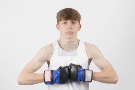 Photo for A 15 year old male teenager boxer, wearing a sleeveless top, touching his gloves togeather - Royalty Free Image
