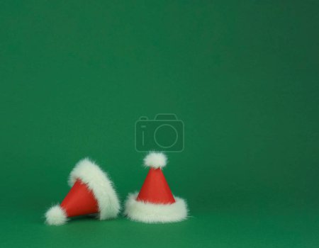 Foto de Dos Santa Clauss rojo con sombreros de plumas blancas sobre fondo verde. Tarjeta de estilo mínimo. Foto de alta calidad - Imagen libre de derechos