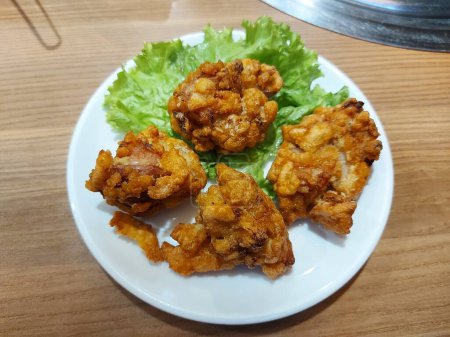 Foto de Pollo karaage o pollo frito estilo japonés. Se sirve en un plato blanco con lechuga. Sabor sabroso - Imagen libre de derechos