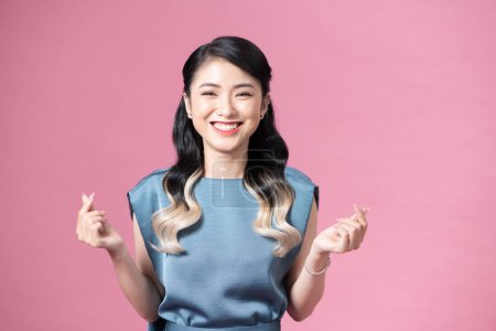 Photo for Young Asian woman showing mini hearts sign isolated on pink background, Spreading love and happiness concept - Royalty Free Image