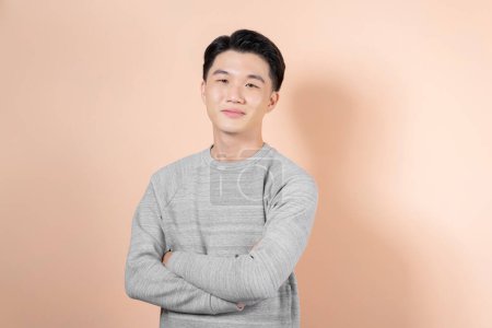 Téléchargez les photos : Young smiling asian man looking at camera isolated on beige background - en image libre de droit