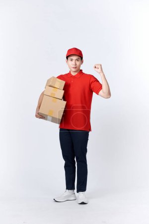 Téléchargez les photos : Portrait d'un beau livreur fort fléchissant son muscle et tenant des paquets de boîtes à pizza. - en image libre de droit