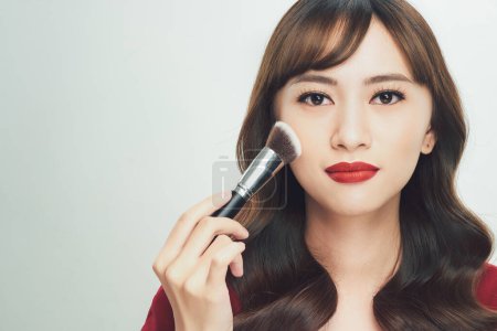 Téléchargez les photos : Beauté asiatique fille bronzage peau avec pinceau de maquillage. Elle sourit et cherche à brosser en poudre, Maquillage naturel - en image libre de droit