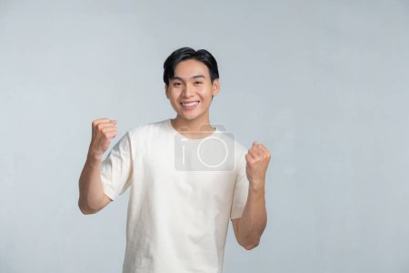 Téléchargez les photos : Un portrait de heureux excité jeune homme asiatique isolé sur fond blanc - en image libre de droit
