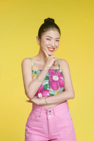 Photo for Beautiful young woman in flower shirt and pink shorts posing against yellow background - Royalty Free Image