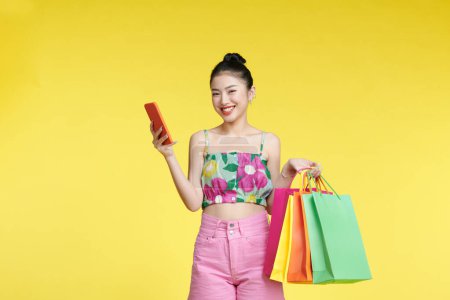Téléchargez les photos : Asian woman are holding shopping bags and smartphone with face happily - en image libre de droit