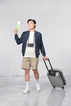 Foto de Retrato de un joven feliz con pasaporte y tarjeta de embarque sobre fondo blanco - Imagen libre de derechos