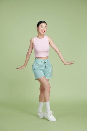 Photo for Full body of happy girl dancing your hands up on green pastel background - Royalty Free Image