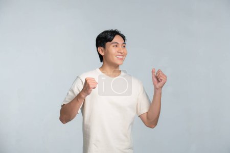 Foto de Guapo feliz hombre emocionado haciendo el gesto ganador con los brazos levantados - Imagen libre de derechos