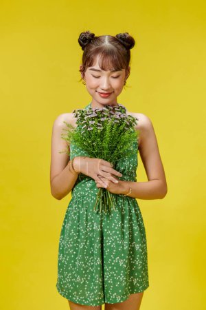 Téléchargez les photos : Femme heureuse en tenue à pois et tenant des fleurs. - en image libre de droit