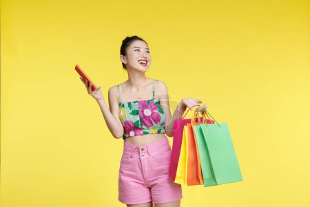 Photo for Attractive Asian smiling young woman Carrying a shopping colorful bags, mobile phone - Royalty Free Image