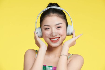 Foto de Mujer joven escuchando música con auriculares aislados sobre fondo amarillo - Imagen libre de derechos