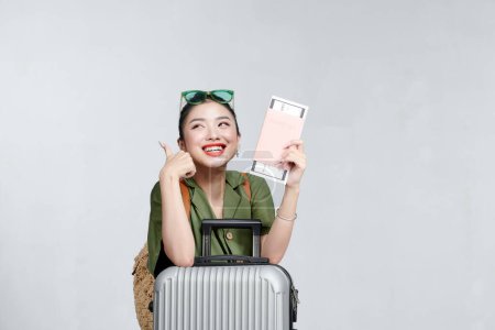 Téléchargez les photos : Femme gaie avec passeport et valise montrant pouces vers le haut - en image libre de droit