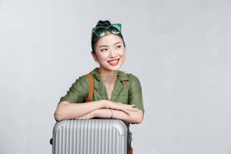 Téléchargez les photos : Voyageur femme avec valise sur fond gris - en image libre de droit
