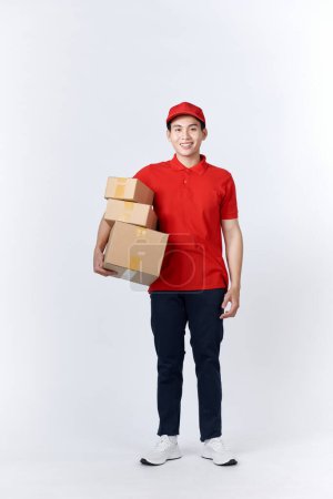 Foto de Retrato sonriente asiático hombre sosteniendo cajas de correos de pie sobre fondo aislado con espacio de copia. - Imagen libre de derechos