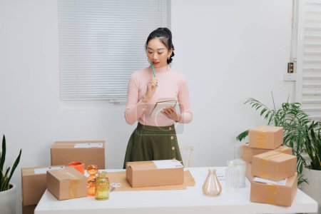 Photo for Start up entrepreneur of young asian woman working with boxes for packaging order for business online and online shopping. - Royalty Free Image