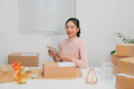Photo for Young beautiful woman checking a parcels, with smiling look happy with her job - Royalty Free Image