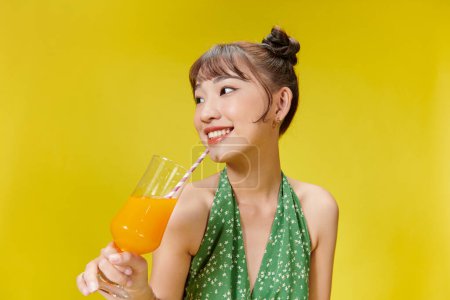 Téléchargez les photos : Belle femme boit cocktail sur fond jaune - en image libre de droit
