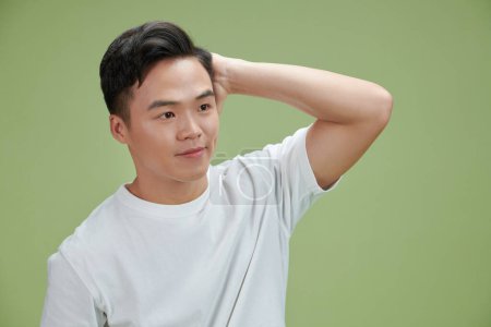 Photo for Confident smiling handsome young man in white t shirt, fixing his perfect hairstyle. - Royalty Free Image