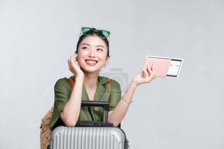 Téléchargez les photos : Enthousiaste asiatique fille montre passeport, billets, sourire heureux, debout avec valise, fond gris - en image libre de droit