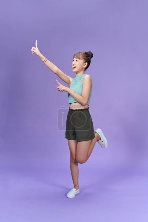 Photo for Full length image of young Asian woman posing on purple background - Royalty Free Image