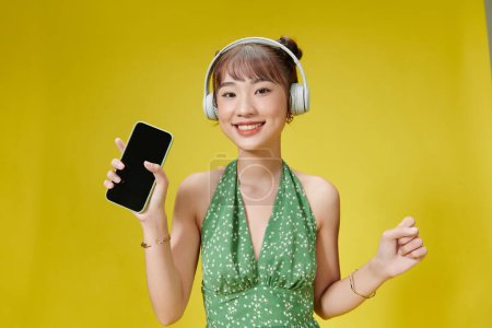 Téléchargez les photos : Femme debout isolée sur fond jaune, écoutant de la musique avec écouteurs, chantant - en image libre de droit