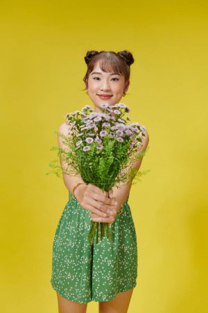 Téléchargez les photos : Femme heureuse en tenue à pois et tenant des fleurs. - en image libre de droit
