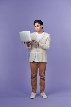Téléchargez les photos : Homme d'affaires intelligent utilisant ordinateur portable isolé sur violet, concept de réussite commerciale - en image libre de droit