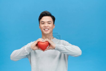 Téléchargez les photos : Jeune homme asiatique heureux tenant coeur rouge prêt pour la Saint-Valentin - en image libre de droit