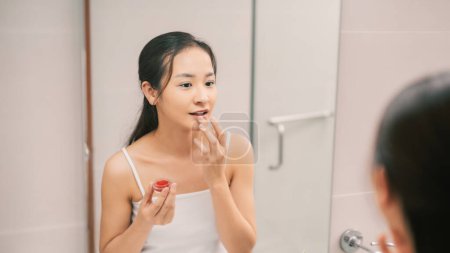 Téléchargez les photos : Jolie asiatique femme putting baume sur lèvres
. - en image libre de droit