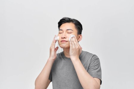 Téléchargez les photos : Asiatique homme lavage son visage avec visage nettoyage mousse - en image libre de droit