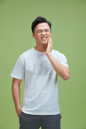 Téléchargez les photos : Asiatique homme sentir mal de dents avec fond vert - en image libre de droit
