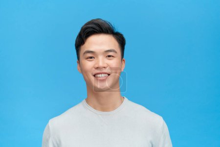Photo for Portrait of a handsome young man smiling against blue background - Royalty Free Image