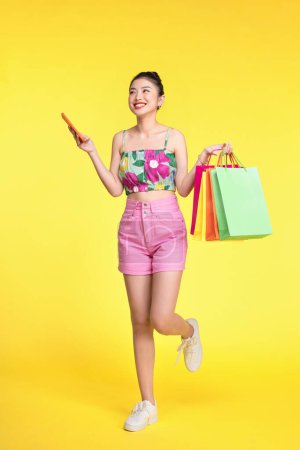 Photo for Portrait of a young woman using mobile phone with shopping bags in her hands. - Royalty Free Image