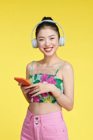 Photo for Cheerful nice woman wearing headphones  standing near empty space with telephone - Royalty Free Image