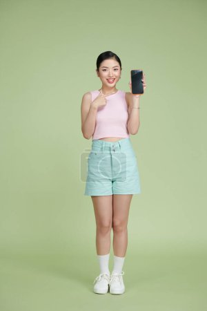Téléchargez les photos : Jeune fille asiatique en utilisant le téléphone sur fond vert - en image libre de droit