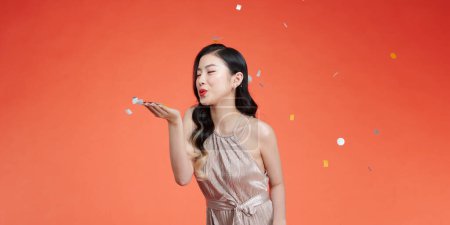 Foto de Bastante sexy mujer asiática y confeti sobre fondo rojo. - Imagen libre de derechos