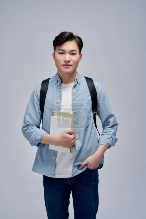 Téléchargez les photos : Souriant heureux asiatique jeune homme étudiant avec sac à dos debout isolé sur fond blanc. - en image libre de droit