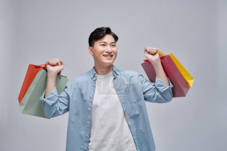 Photo for Asian young man holding shopping bags, full length portrait isolated. - Royalty Free Image