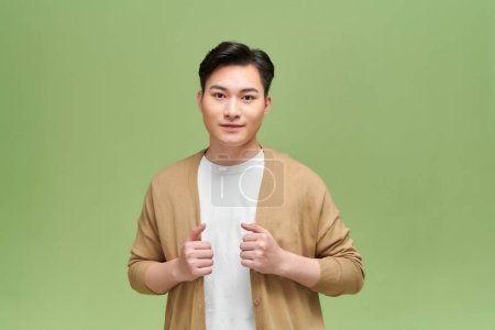 Photo for Casual handsome man wearing cardigan smiling on green background - Royalty Free Image