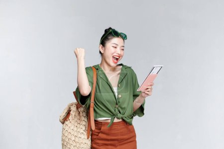 Téléchargez les photos : Voyageur fun femme porter des vêtements décontractés tenir passeport billet faire geste gagnant - en image libre de droit