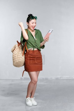 Foto de Viajero turista asiática mujer en posesión de pasaporte, billete haciendo gesto ganador aislado sobre fondo blanco - Imagen libre de derechos