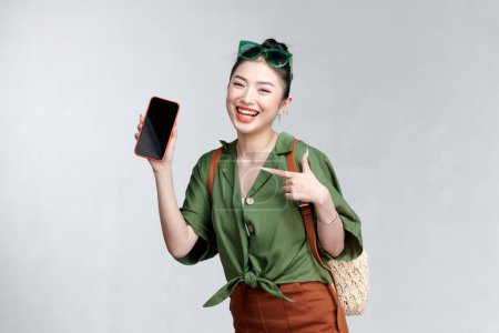 Téléchargez les photos : Jeune femme montrant smartphone pour présenter et pointer quelque chose sur un voyage d'été - en image libre de droit